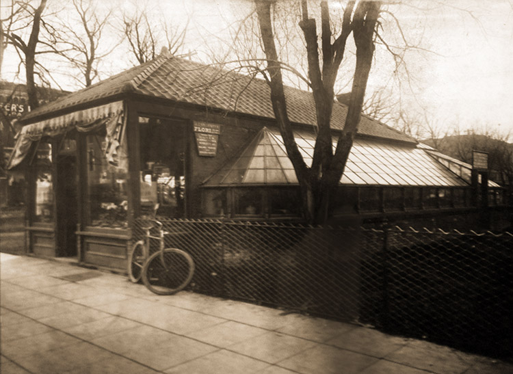 A bicycle leans on the fence outside our small original location, circa 1910